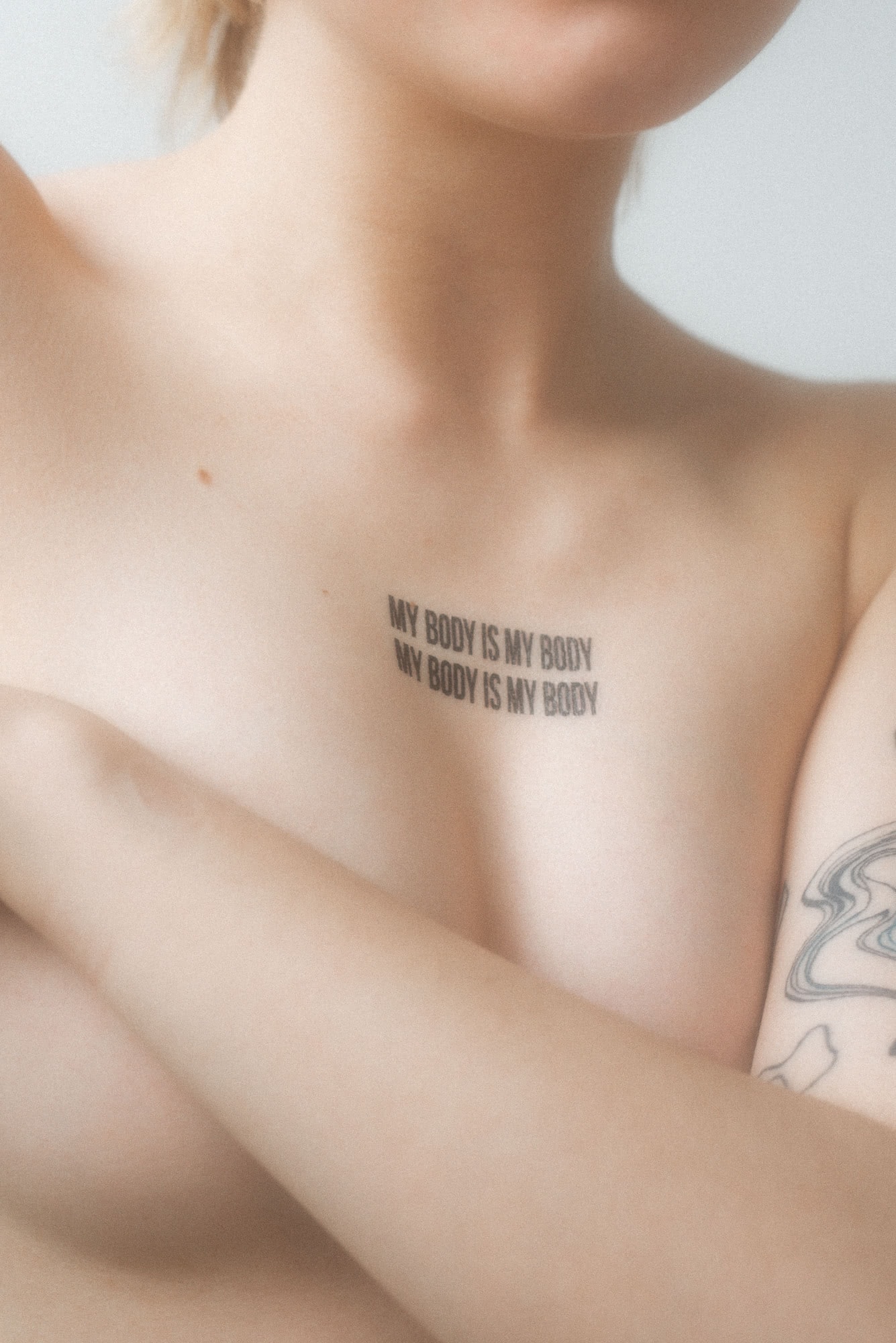 Naga osoba z tatuażem nad piersiami - My body is my body - czyli - Moje ciało jest moje.