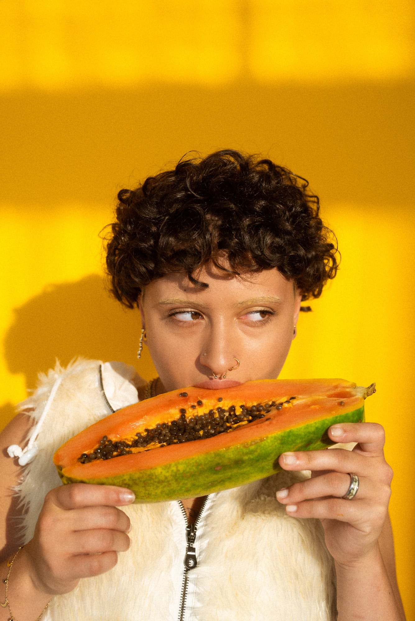Młoda dziewczyna namiętnie gryzie owoc papaji.