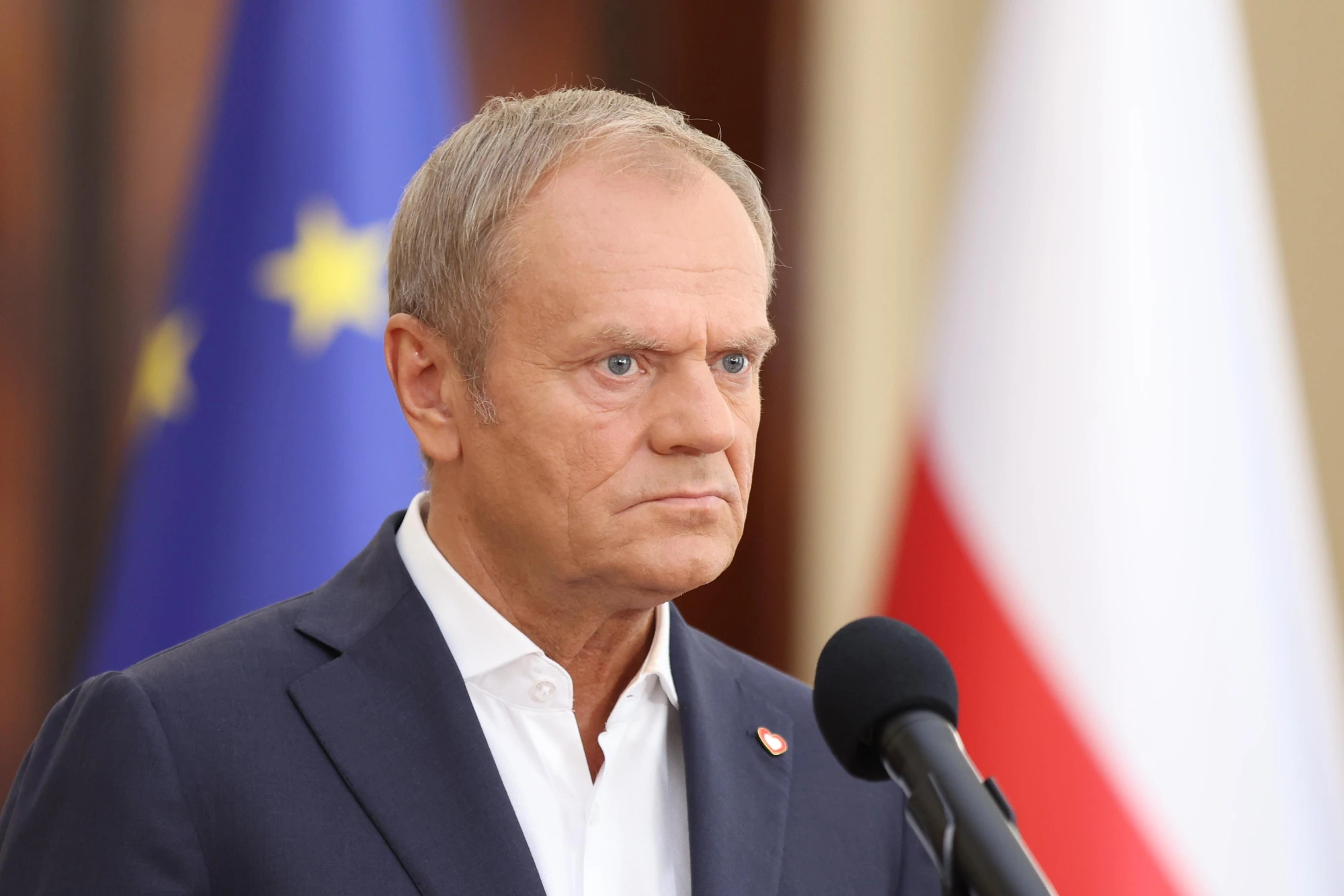 Donald Tusk w tle logo PO oraz flaga Polski.