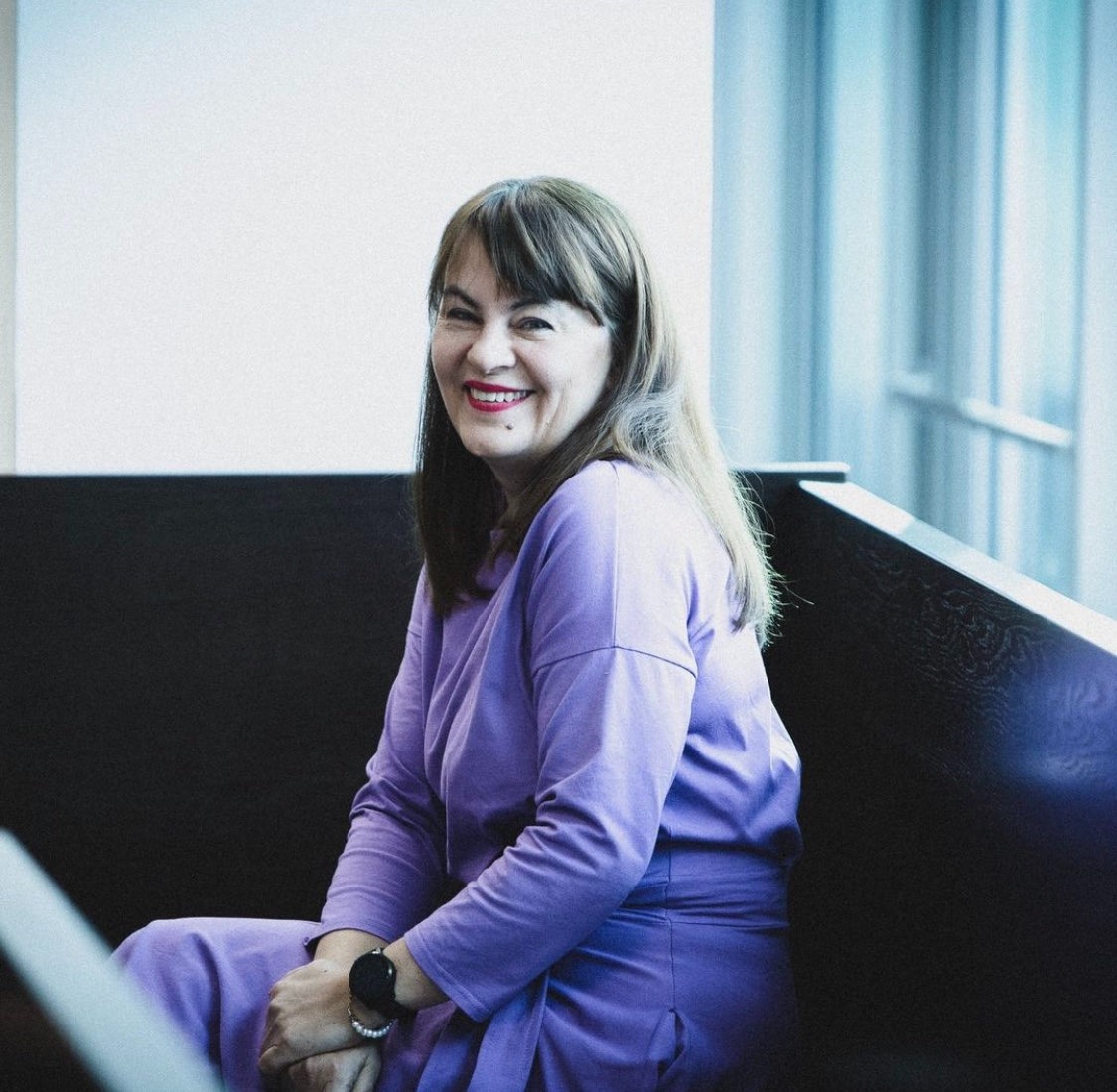 Uśmiechnięta Justyna Wydrzyńska zasiana na ławie oskrażonych za próbę pomocy w przerwaniu ciąży.